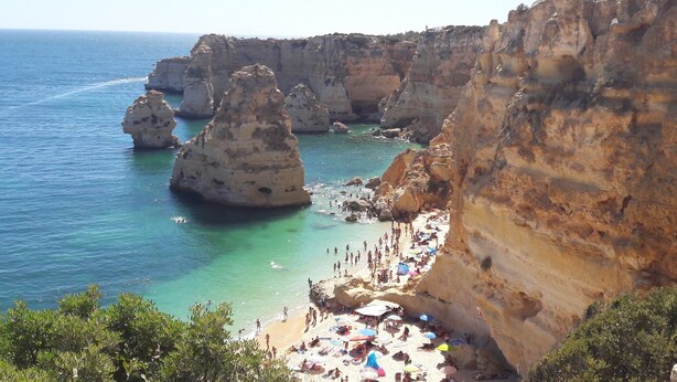 Una playa costera con acantilados rocosos y aguas turquesas cristalinas.