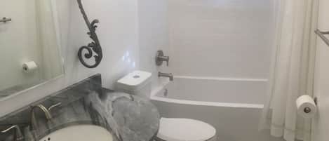 Une salle de bain avec un lavabo en marbre, des toilettes blanches et une baignoire.