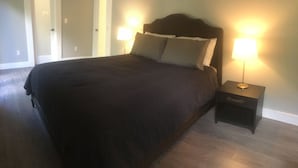 A bedroom with a large bed, two bedside tables with lamps, and a door leading to another room. - Newly Renovated 4/3 Upscale East Boca Home (Boca Raton)