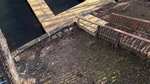 Een houten steiger die uitsteekt in een rustig meer, met een klein houten platform en een bankje.
