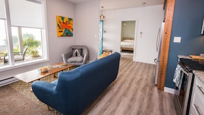 Uma sala de estar moderna com um sofá azul, uma poltrona cinza e uma mesa de jantar de madeira.