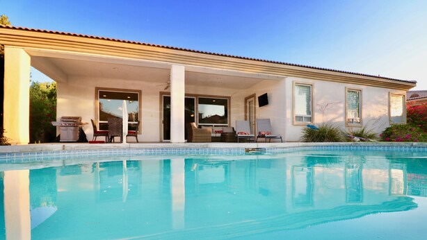 A poolside area with a covered patio, outdoor seating, and a view of the pool. - An Elegant Palm Desert Home, Great Nightly Rate! (Palm Desert)