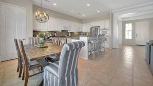 A spacious kitchen with white cabinets, a wooden dining table, and a chandelier. - An Elegant Palm Desert Home, Great Nightly Rate! (Palm Desert)