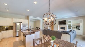 A spacious kitchen with a central island, stainless steel appliances, and a dining area with a wooden table. - An Elegant Palm Desert Home, Great Nightly Rate! (Palm Desert)