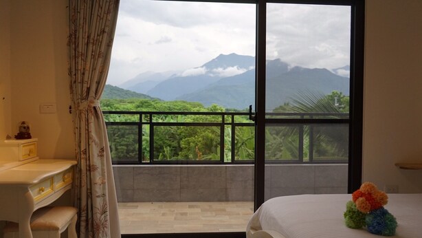A bedroom with a balcony, a desk, and a bed with a colorful toy. - Hu Moon Lake (Shoufeng)