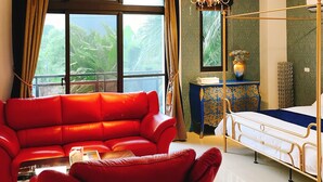 A room with a red sofa, a bed with a gold frame, a chandelier, and a view of greenery through large windows. - Hu Moon Lake (Shoufeng)