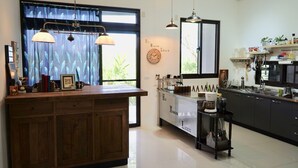 A modern kitchen with a wooden island, pendant lights, and a view of a lake. - Hu Moon Lake (Shoufeng)