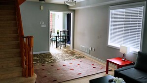 A living room with a staircase, a dining area, and a large window with blinds. - Entire 3 Bedroom Townhouse in Markham (Markham)