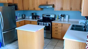 A kitchen with wooden cabinets, stainless steel appliances, a central island, and a double sink. - Entire 3 Bedroom Townhouse in Markham (Markham)