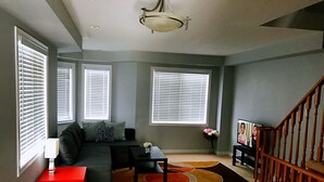A living room with a sectional sofa, a red side table, a coffee table, and a staircase. - Entire 3 Bedroom Townhouse in Markham (Markham)