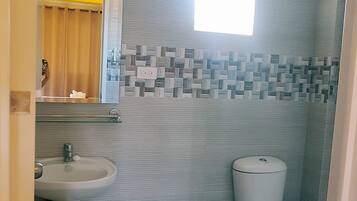 Un baño con lavamanos pedestal, inodoro y pared con diseño.