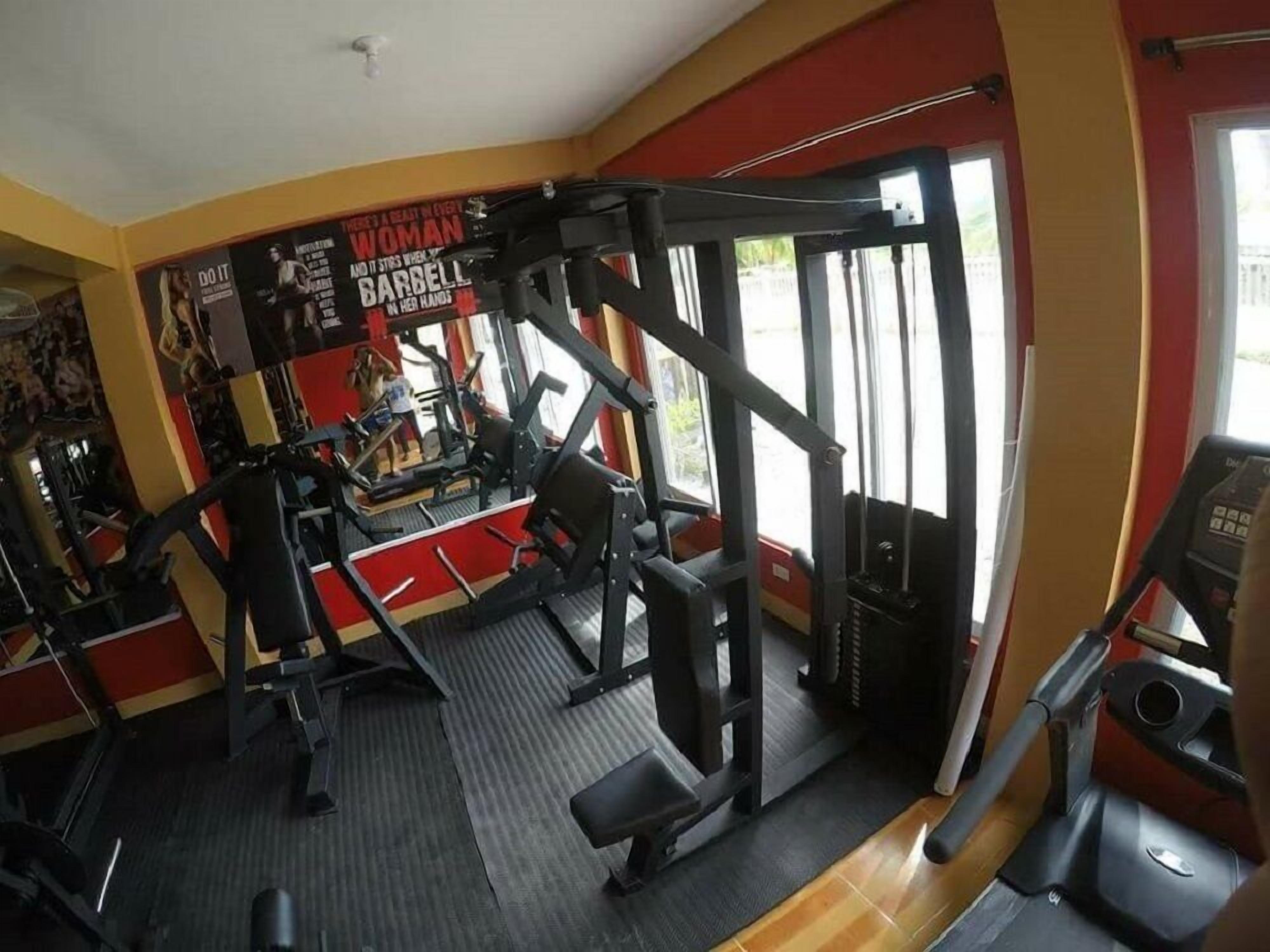 A gym with various exercise equipment, including a squat rack and a treadmill.