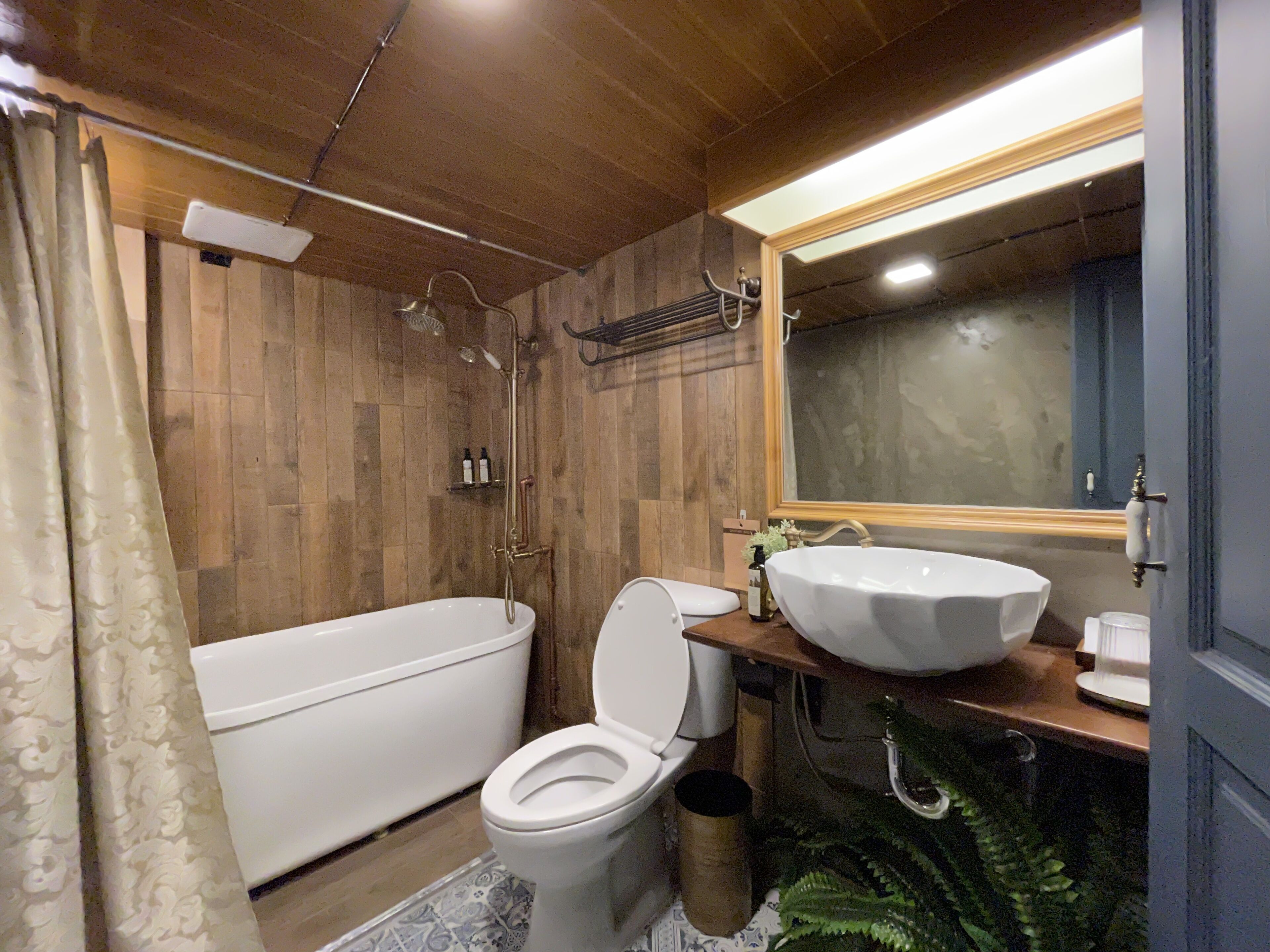 Ein Badezimmer mit Holzboden, einer Badewanne, einer Toilette und einem Waschbecken.