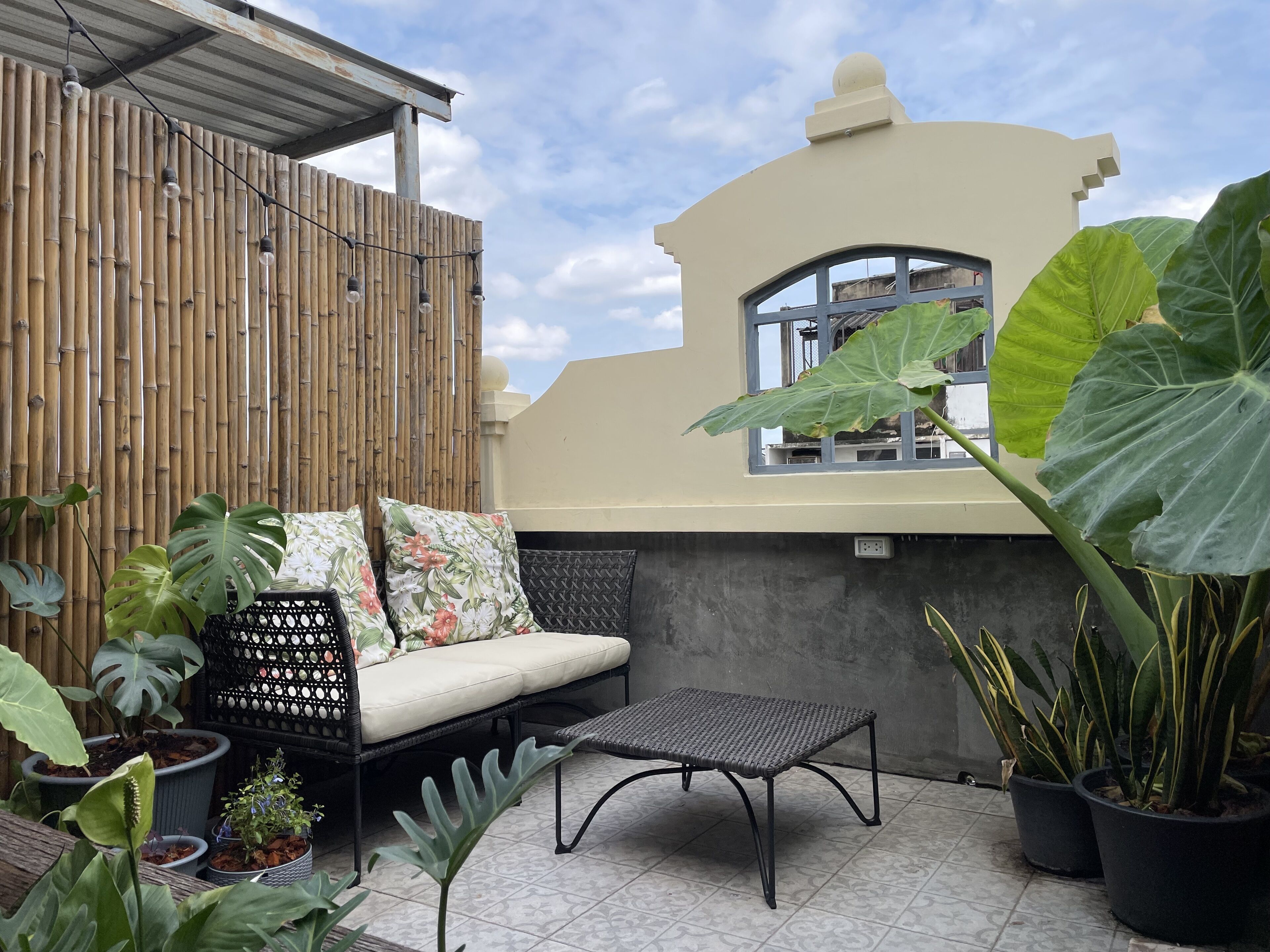 A patio area with a cushioned seating arrangement, a small table, and potted plants.