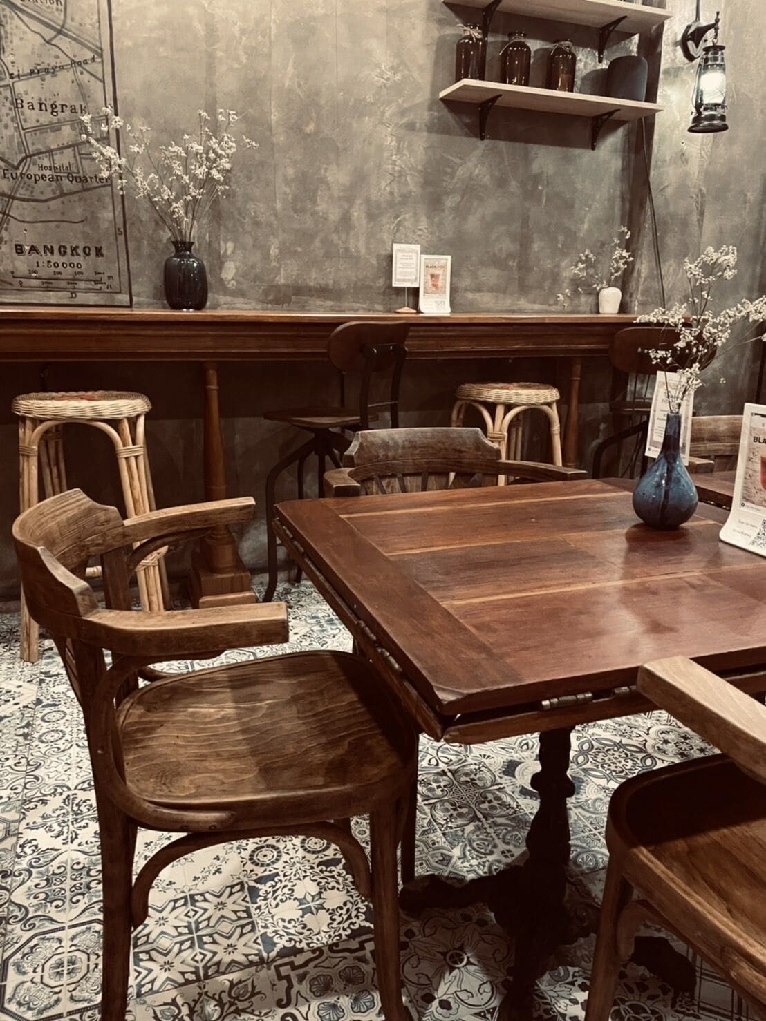 A wooden dining table with chairs, a vase with flowers, and a map on the wall.