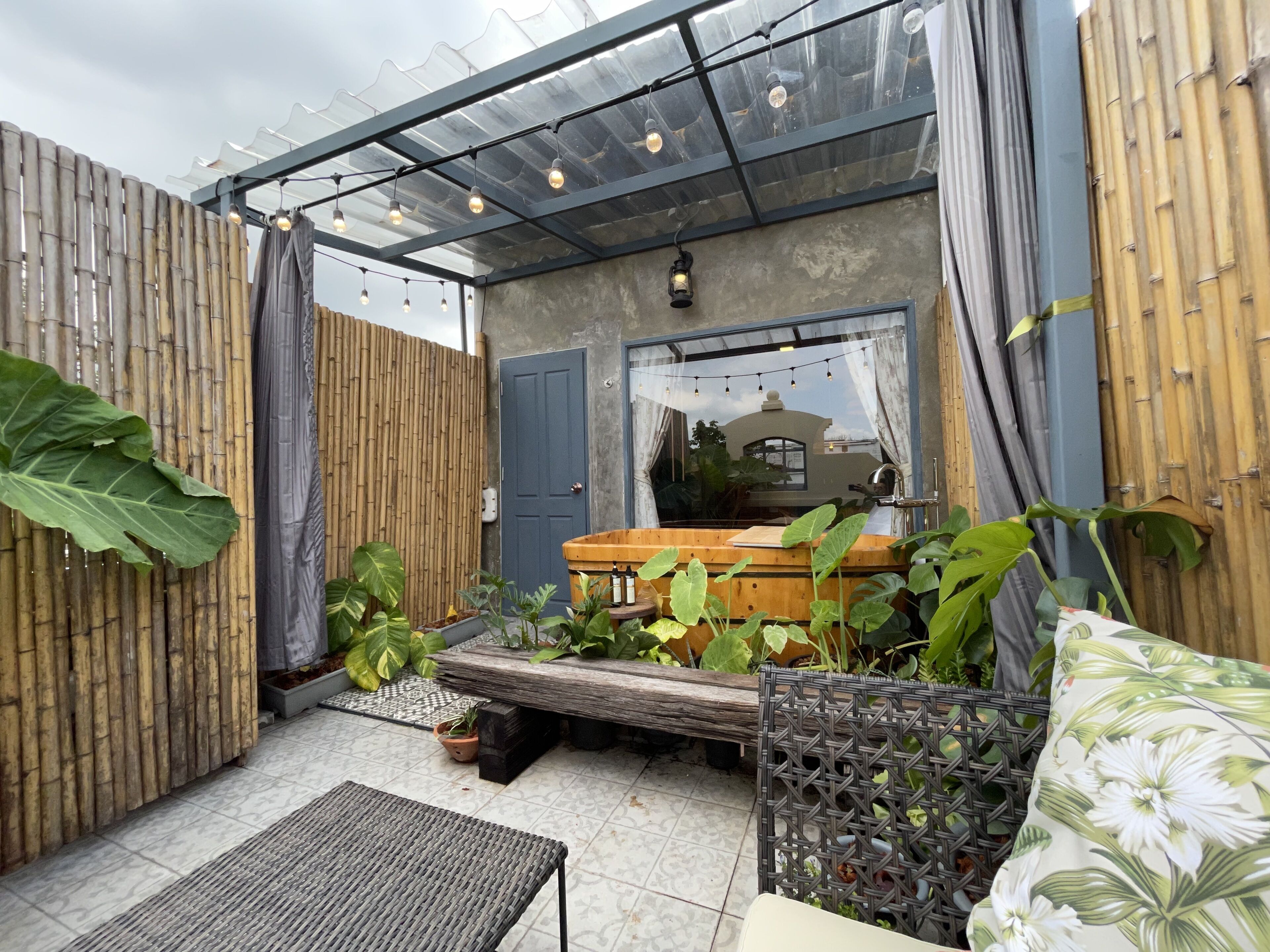A covered patio area with a wooden bench, potted plants, and a table.