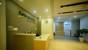 A reception desk with a clock above it, a fire extinguisher, and a potted plant in the lobby. - Karta Riverview Apartment (Ho Chi Minh City)