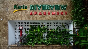 A sign for Karta Riverside Apartment with a modern design, including a neon sign and a planter with green plants. - Karta Riverview Apartment (Ho Chi Minh City)