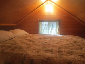 A bedroom with a bed, pillows, and a window with curtains.