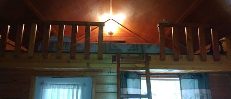 A wooden interior with a staircase, a window with curtains, and a light fixture.
