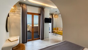 Habitació d'hotel moderna amb un balcó, un sofà i una televisió.