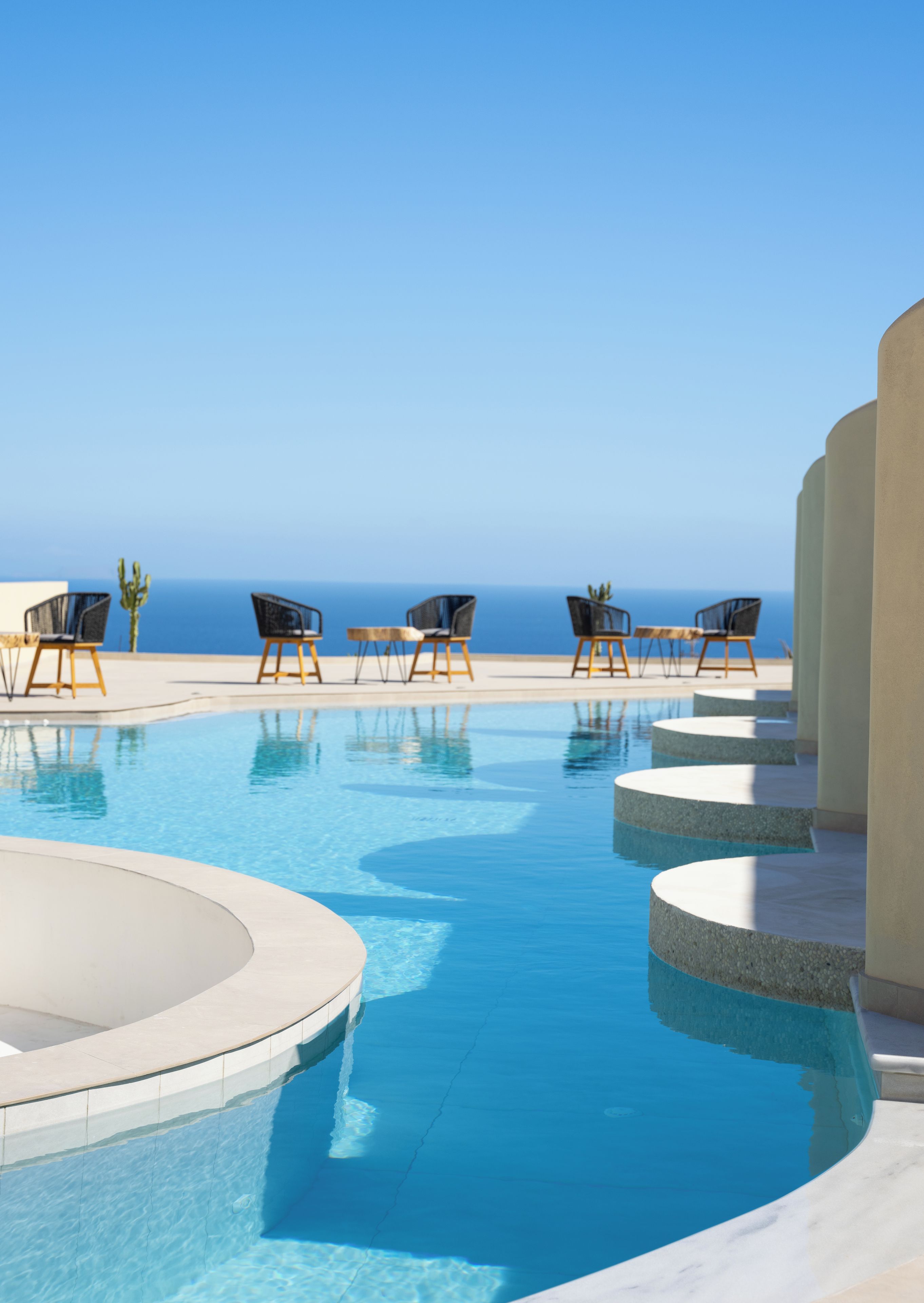 Ein Poolbereich mit Liegestühlen und Blick auf den Ozean.
