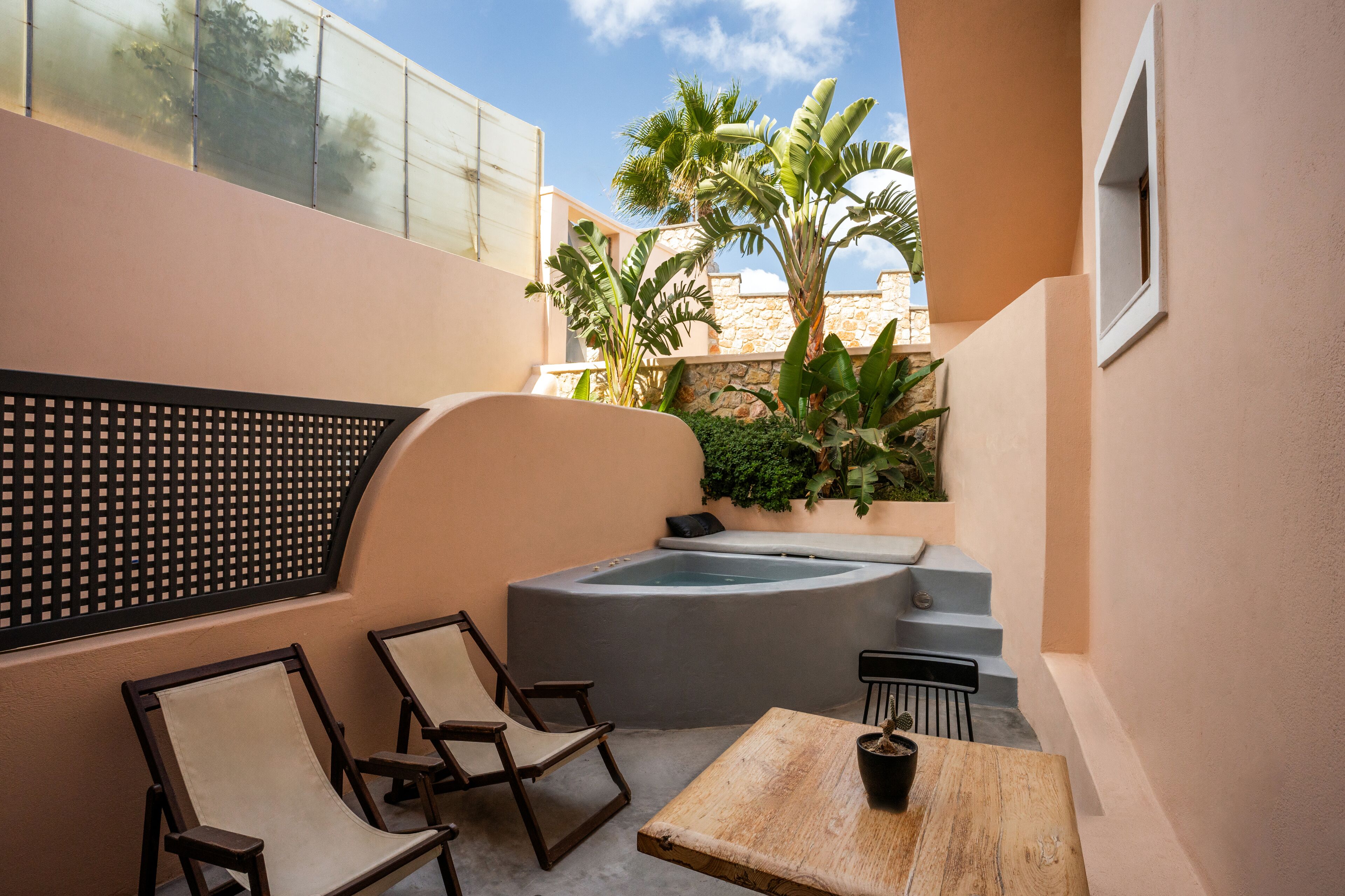 Un área de spa con hidromasaje, asientos y plantas.