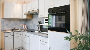Een moderne keuken met witte kastjes, een ingebouwde oven en een magnetron.