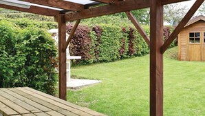 Een houten pergola met een picknicktafel in een tuin.