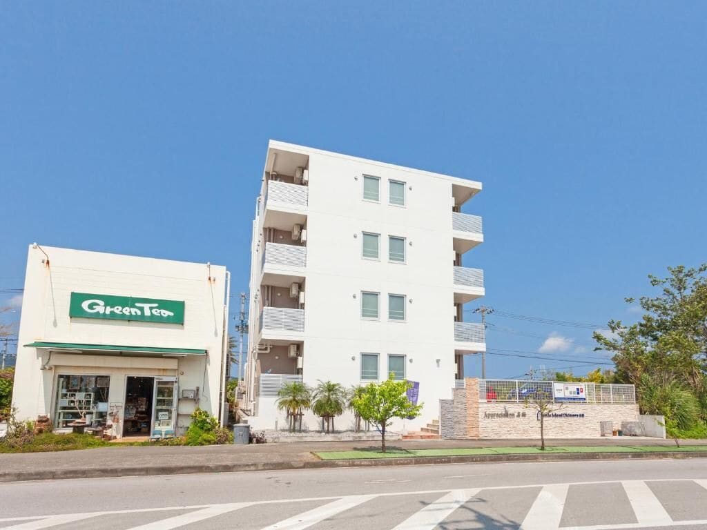 Un bâtiment à deux étages avec une devanture verte portant l’inscription « Green Tea » et une enseigne indiquant « Appreciation 4.0 ».