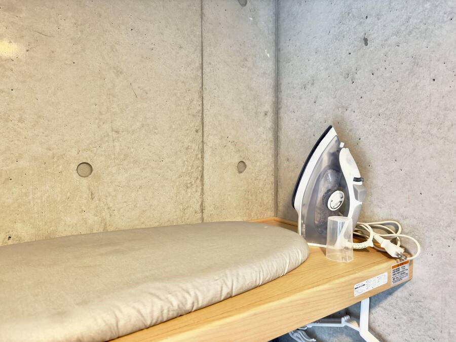 Una habitación pequeña y funcional con un banco de madera y una tabla de planchar.