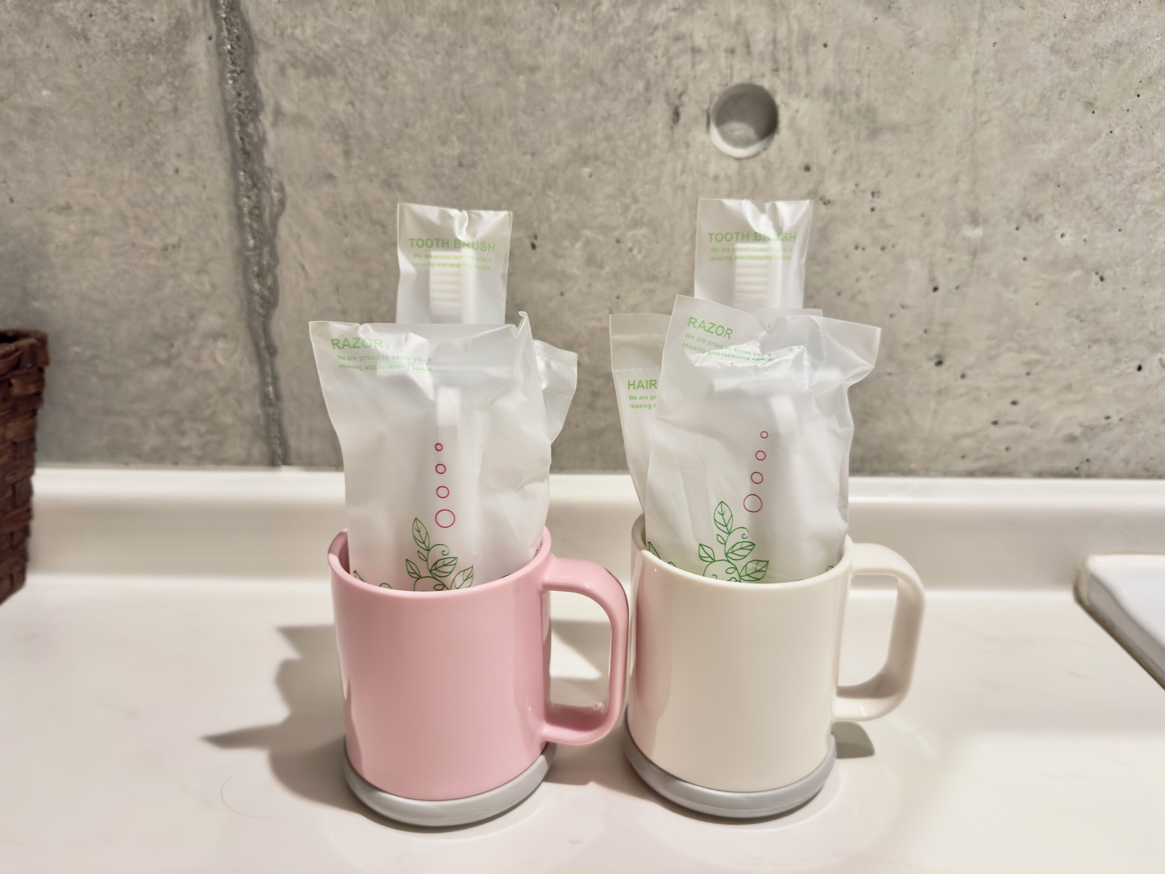 Two mugs with packages of personal care items.
