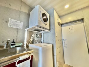 A compact laundry room with a washing machine, a dryer, and a sink. - Little Island Okinawa Nago (Nago)