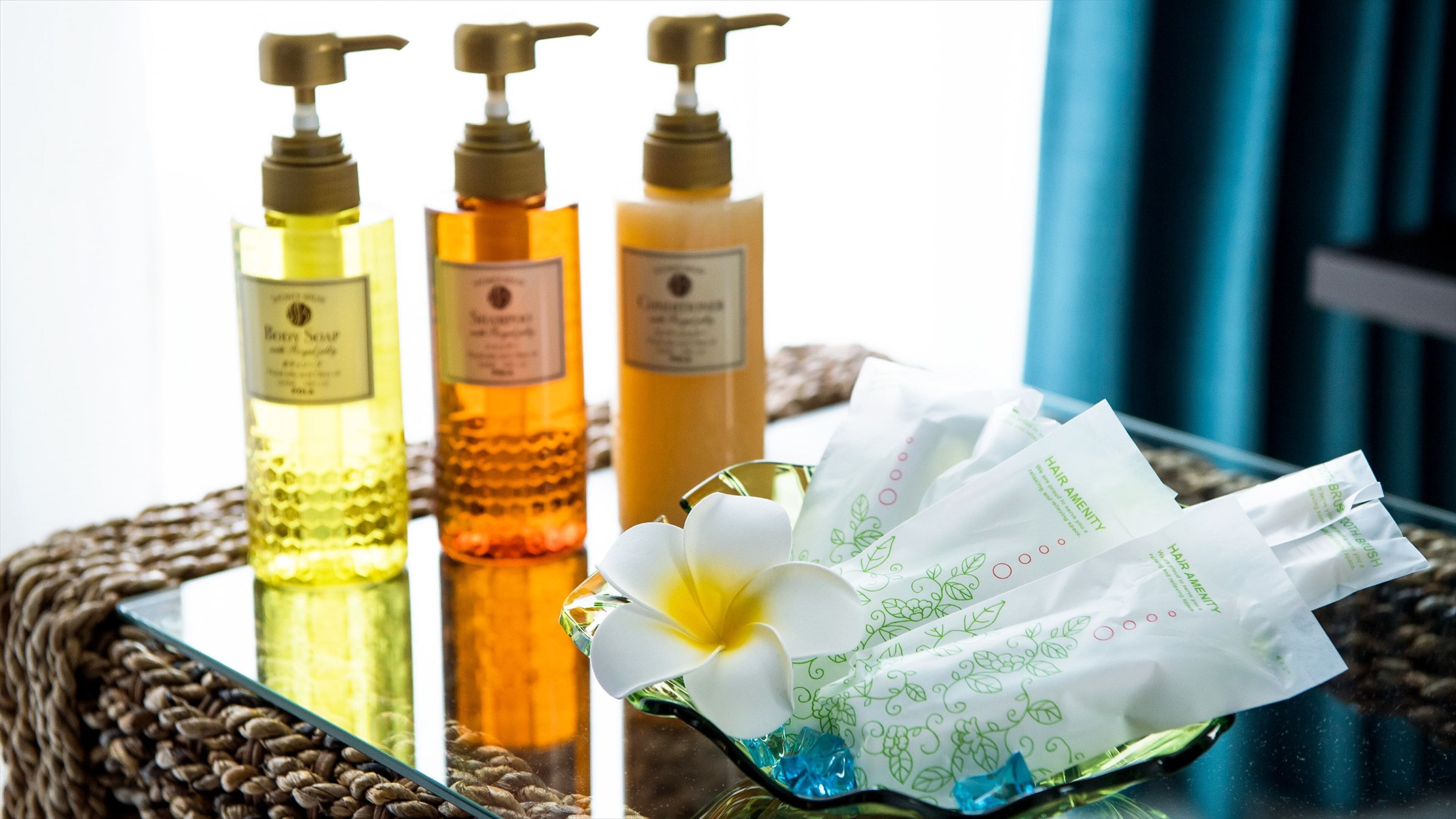Three bottles of hair care products on a glass tray with a white flower.