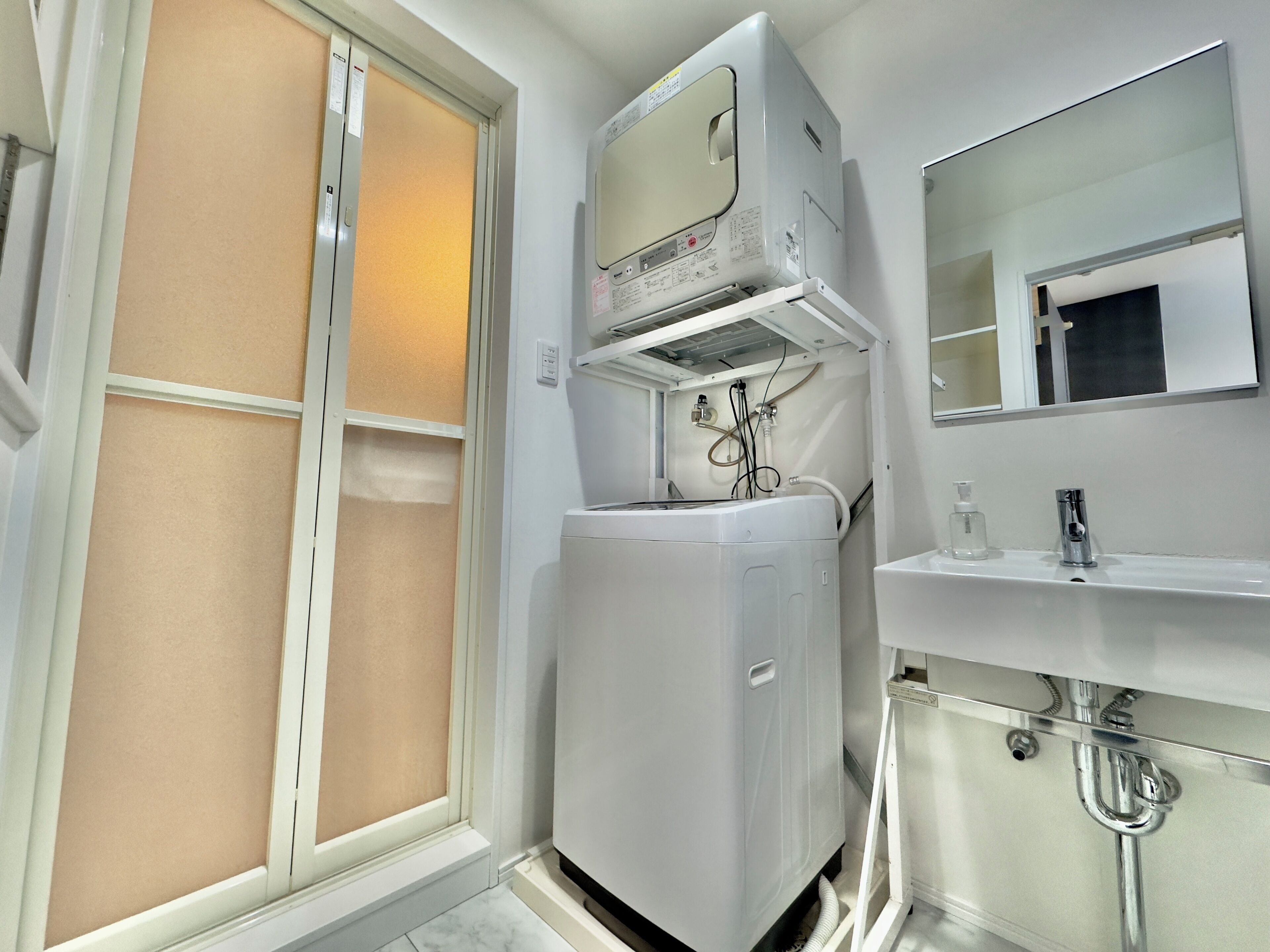 A compact bathroom with a built-in washer and dryer, a mirror, and a sink.