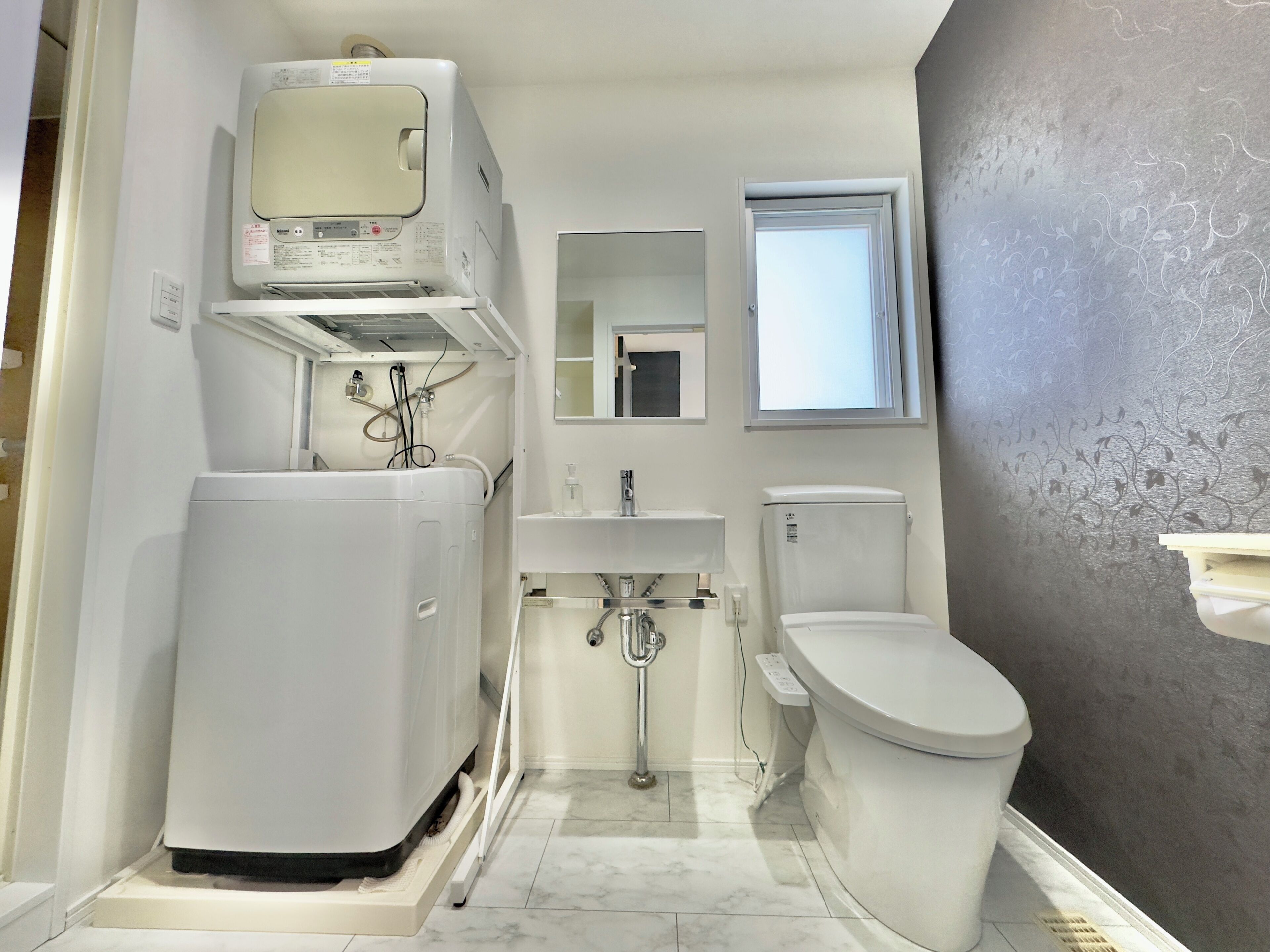 Une petite salle de bain équipée d’un lave-linge intégré, de toilettes et d’un lavabo.