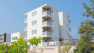 A modern multi-story hotel with balconies, a sign for 'Green Tree', and a 'Little Island of Dreams' sign.