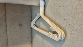 A white, uniquely shaped hanger with a curved design, attached to a white pipe on a concrete floor.
