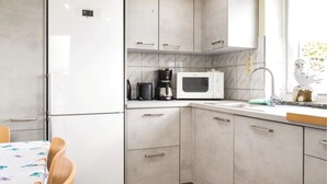 A compact kitchen with a refrigerator, microwave, coffee maker, and a sink.