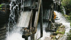 Una estructura de madera rústica con una noria y una pequeña cascada.