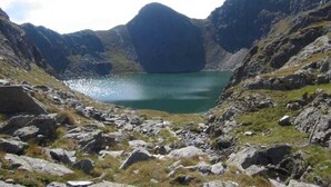 Paisaje montañoso con un lago rodeado de terreno rocoso.