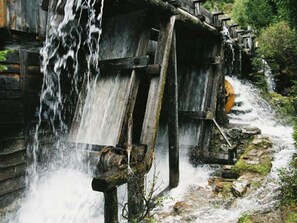 A rustic wooden structure with a water wheel and a small waterfall.