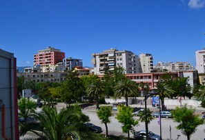 A cityscape with multi-story buildings, palm trees, and a clear blue sky.