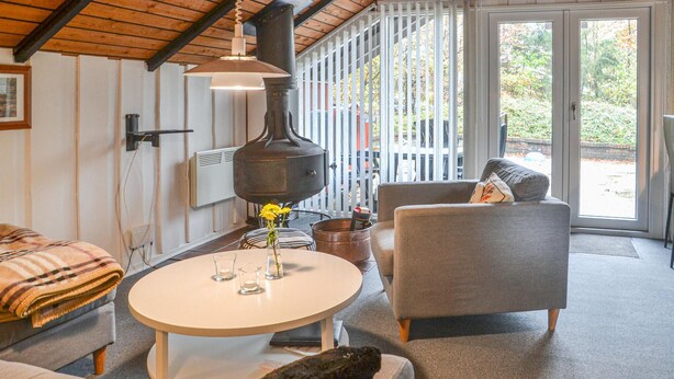 Un salon chaleureux avec une table ronde, un canapé, un fauteuil et une cheminée.