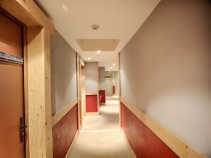 Un couloir aux murs lambrés, une porte rouge et une pancarte indiquant le numéro de la chambre : 422.