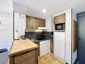 A compact kitchen with wooden cabinets, a microwave, a dishwasher, and a wooden countertop.
