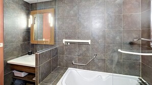 A modern bathroom with a bathtub, a sink, a mirror, and a shower area.