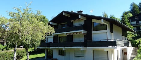 Una casa moderna de dos pisos amb un balcó, un garatge i un jardí ben cuidat.