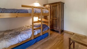 Kerrossänky, jonka yhteydessä on puinen kaappi ja tuoli, ja huoneessa on puulattia.