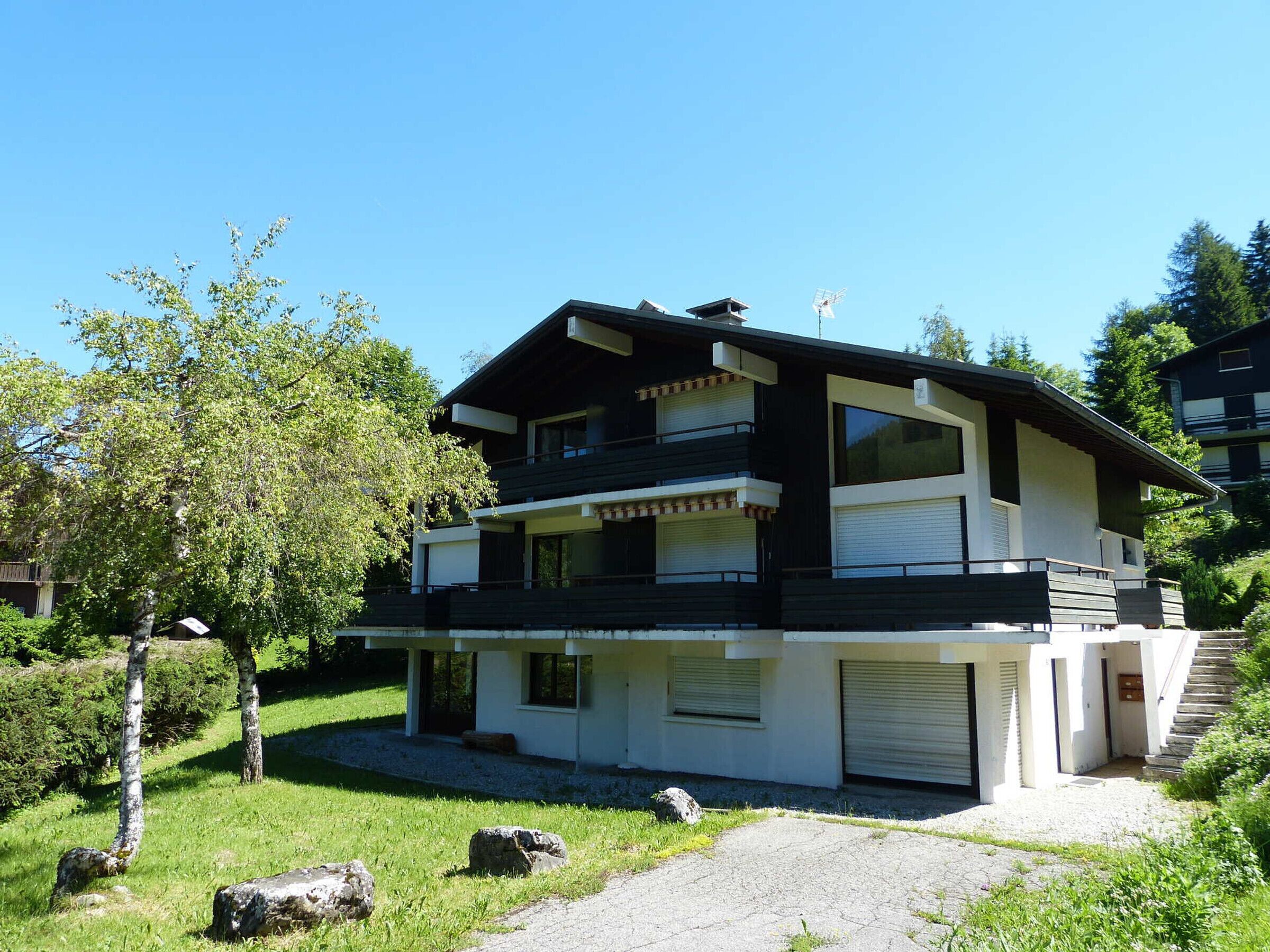 A two-story modern house with a balcony, a garage, and a well-maintained garden.